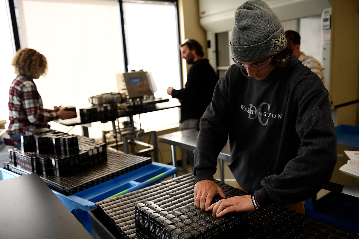 BOULDER, CO - MARCH 10: CW Hemp lab technician Chris Burns taking boxes to have the expiration date and codes printed on the boxes as Breezy Lash runs them through the printer and Mike Saya boxes them. March 10, 2017, Boulder, Colorado. (Photo by Joe Amon/The Denver Post)