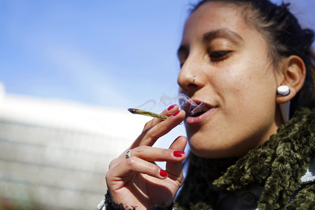 Luisina Mezquita smokes a joint of legal marijuana she just bought at a pharmacy in Montevideo, Uruguay, Wednesday, July 19, 2017. Marijuana is going on sale at 16 pharmacies in Uruguay, the final step in applying a 2013 law that made the South American nation the first to legalize a pot market covering the entire chain from plants to purchase. (AP Photo/Matilde Campodonico)